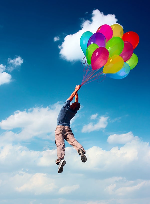 風船につかまっている男性が空に浮かんでいる